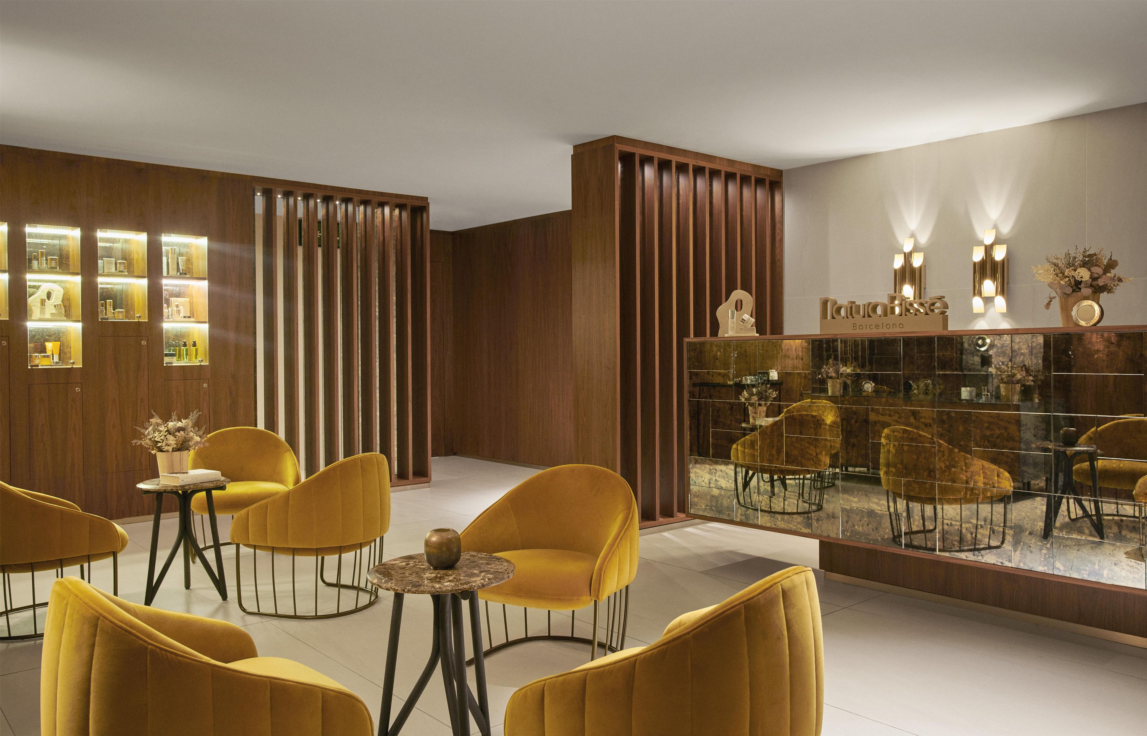 A modern interior with yellow chairs, a wooden partition, and a glass display case with items.