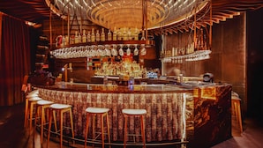 A bar area with a circular chandelier, bar stools, and a variety of bottles and glasses. - Grand Hyatt Barcelona (Barcelona)
