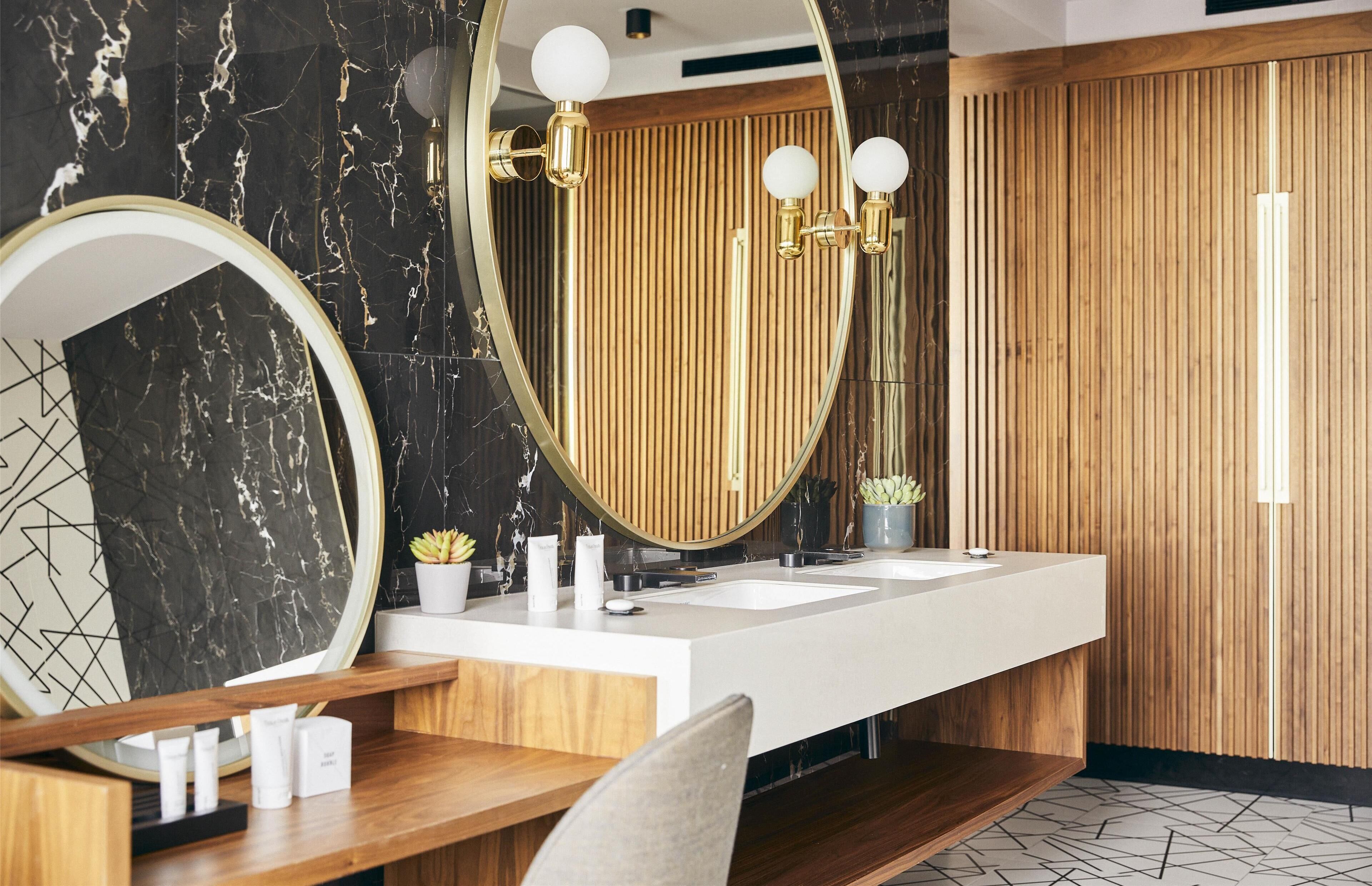 A modern bathroom with a large mirror, two sinks, and wooden paneling.