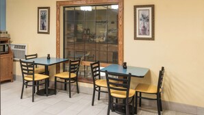 A dining area with a glass partition, wooden chairs, and a blue table.