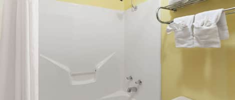 A bathroom with a white bathtub, a shower, and a toilet. There are towels on a rack above the toilet.