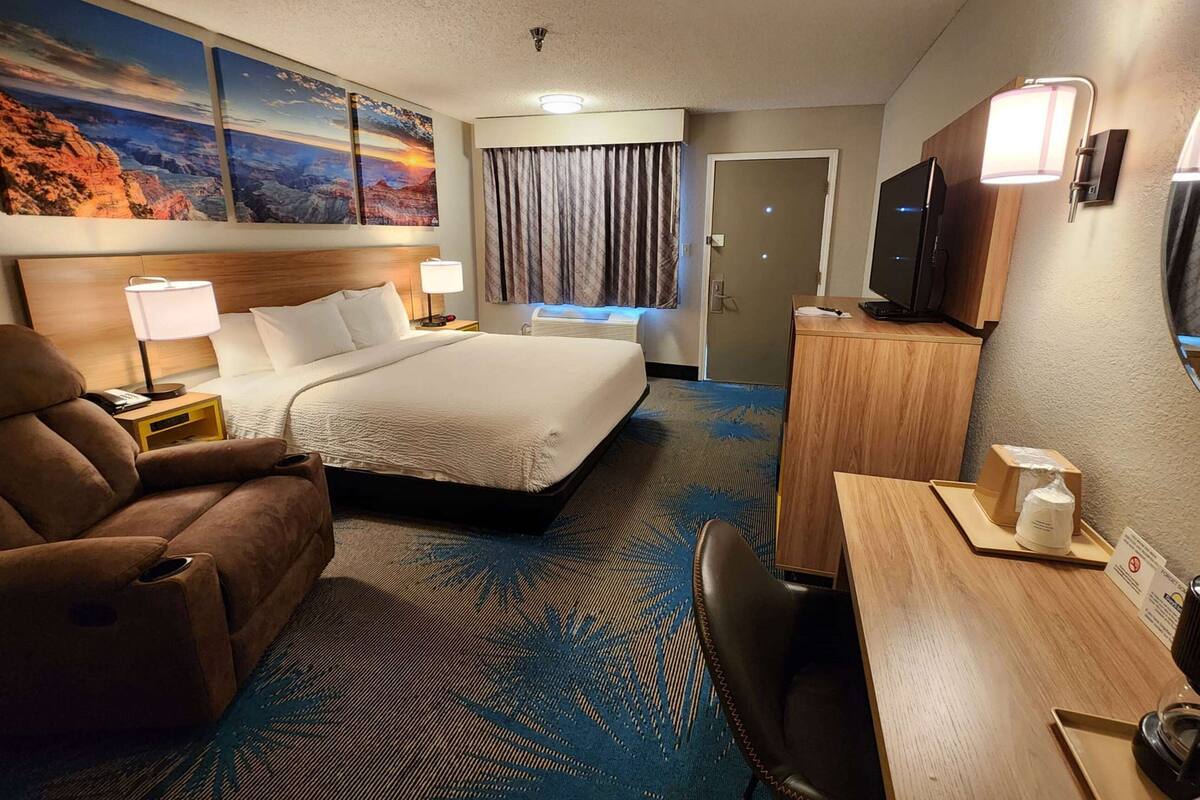 A hotel room with a large bed, a desk with a computer, a TV, and a chair.