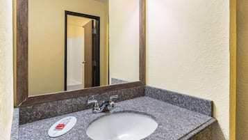 A bathroom with a granite countertop, a white sink, and a mirror.