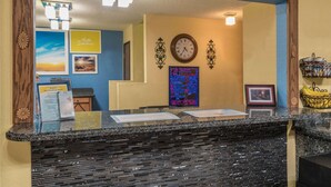 A hotel reception area with a marble counter, a clock, framed pictures, and a wall-mounted sign.