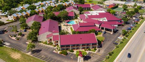 An aerial view of a residential area with houses, a swimming pool, and a parking lot.