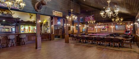 A bar area with wooden flooring, chandeliers, and a sign that reads "For the Love of Beer."