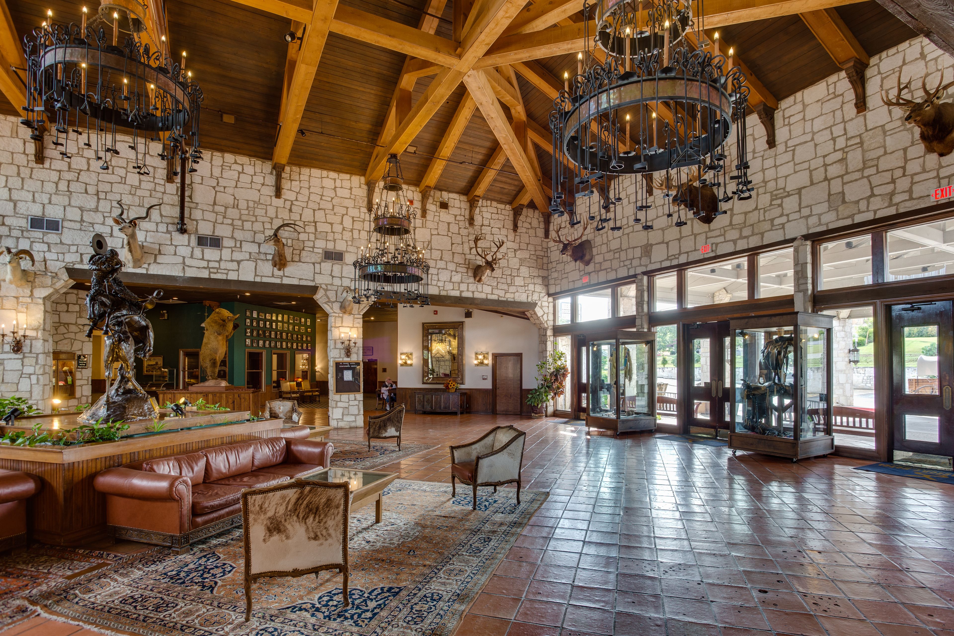 A spacious lobby with a high ceiling, stone walls, and a large chandelier.