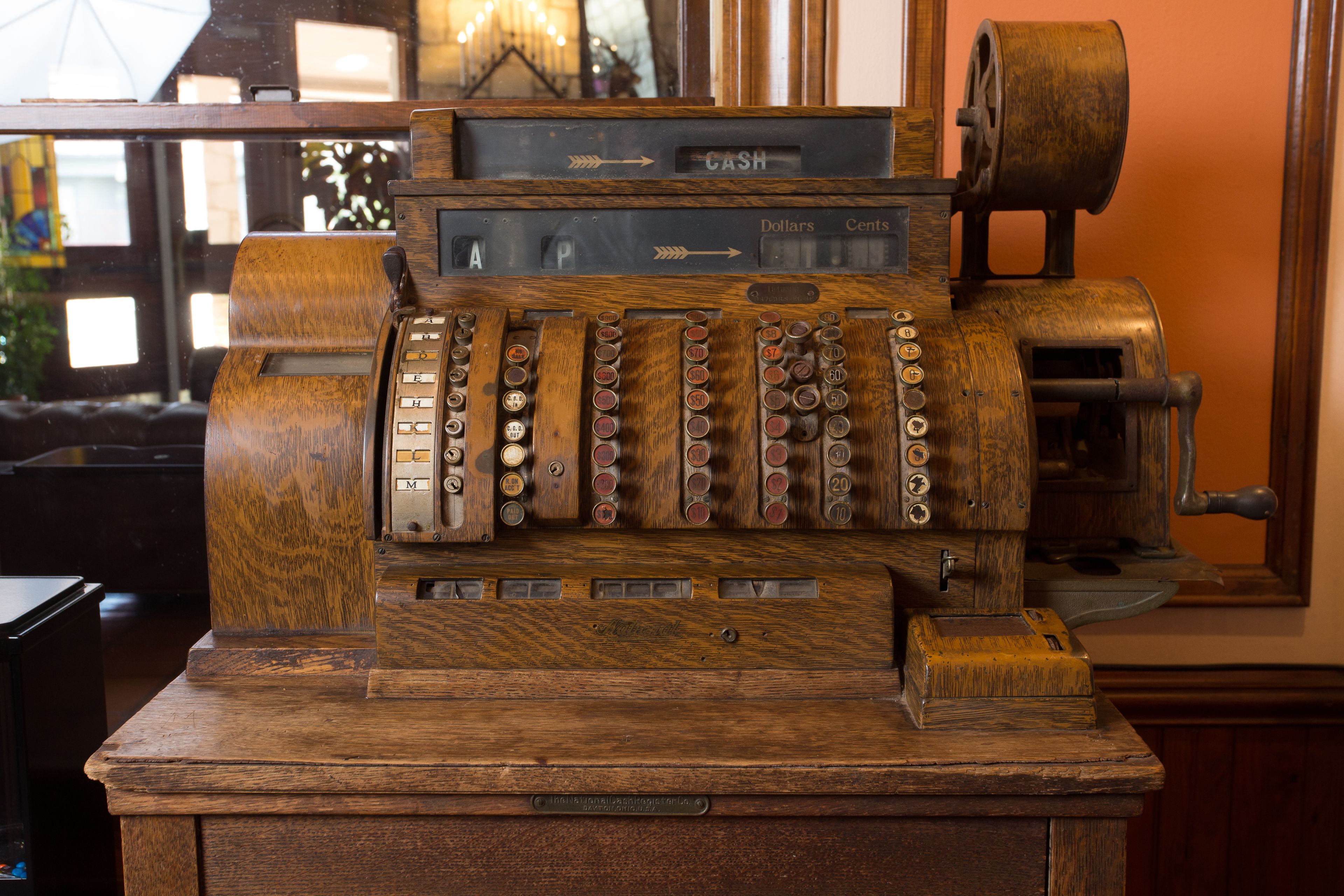 A vintage cash register with a wooden finish and a cash drawer.