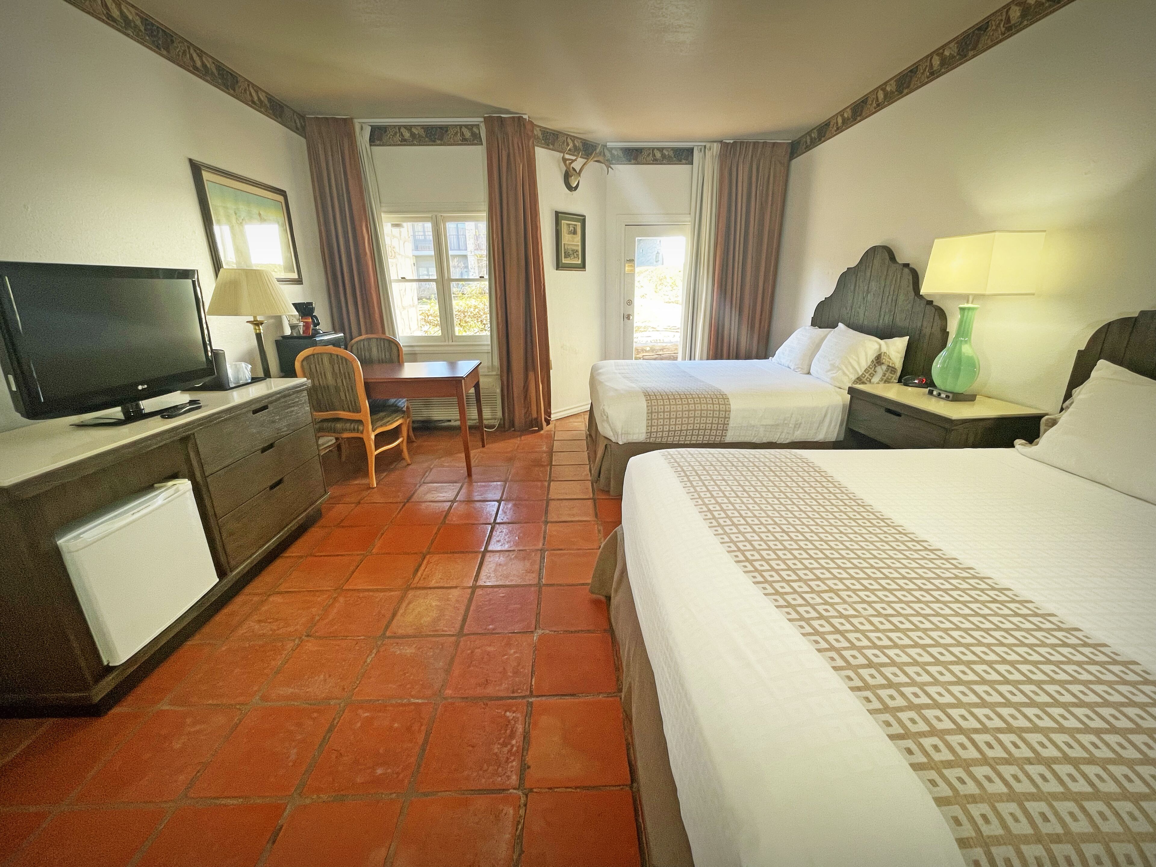 A hotel room with a bed, a desk, a television, and a chair.