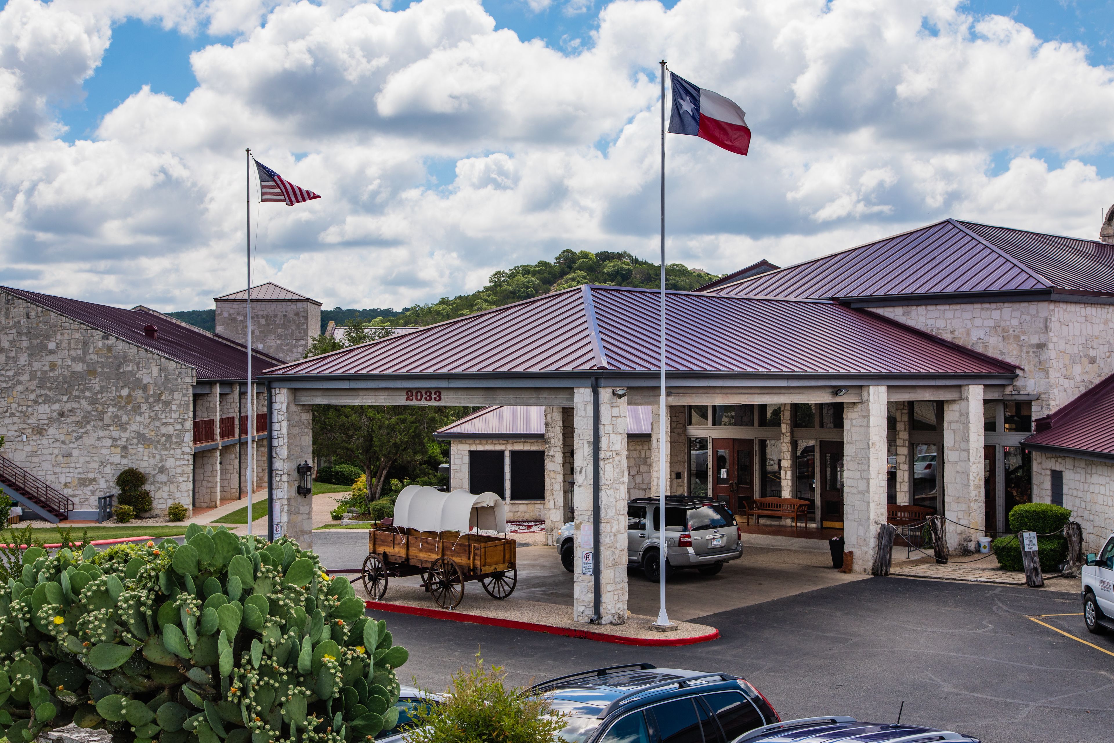 A hotel with a covered entrance, stone facade, and a Texas flag.