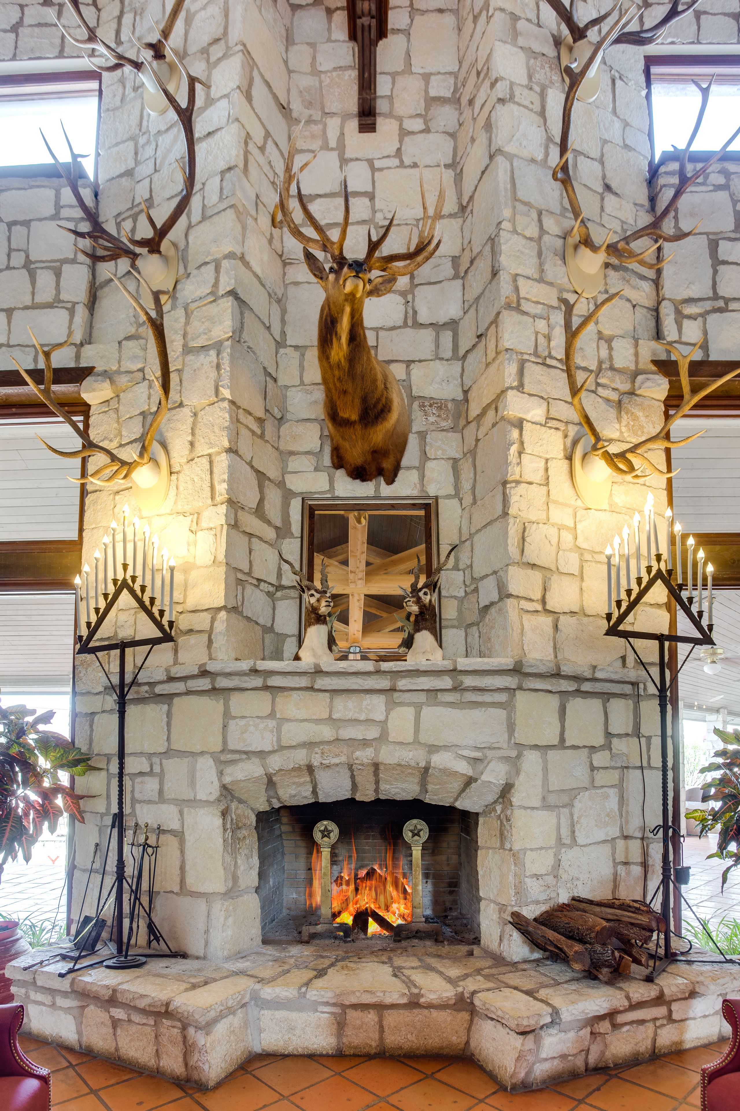 A stone fireplace with antlers mounted above and a lit fire below.