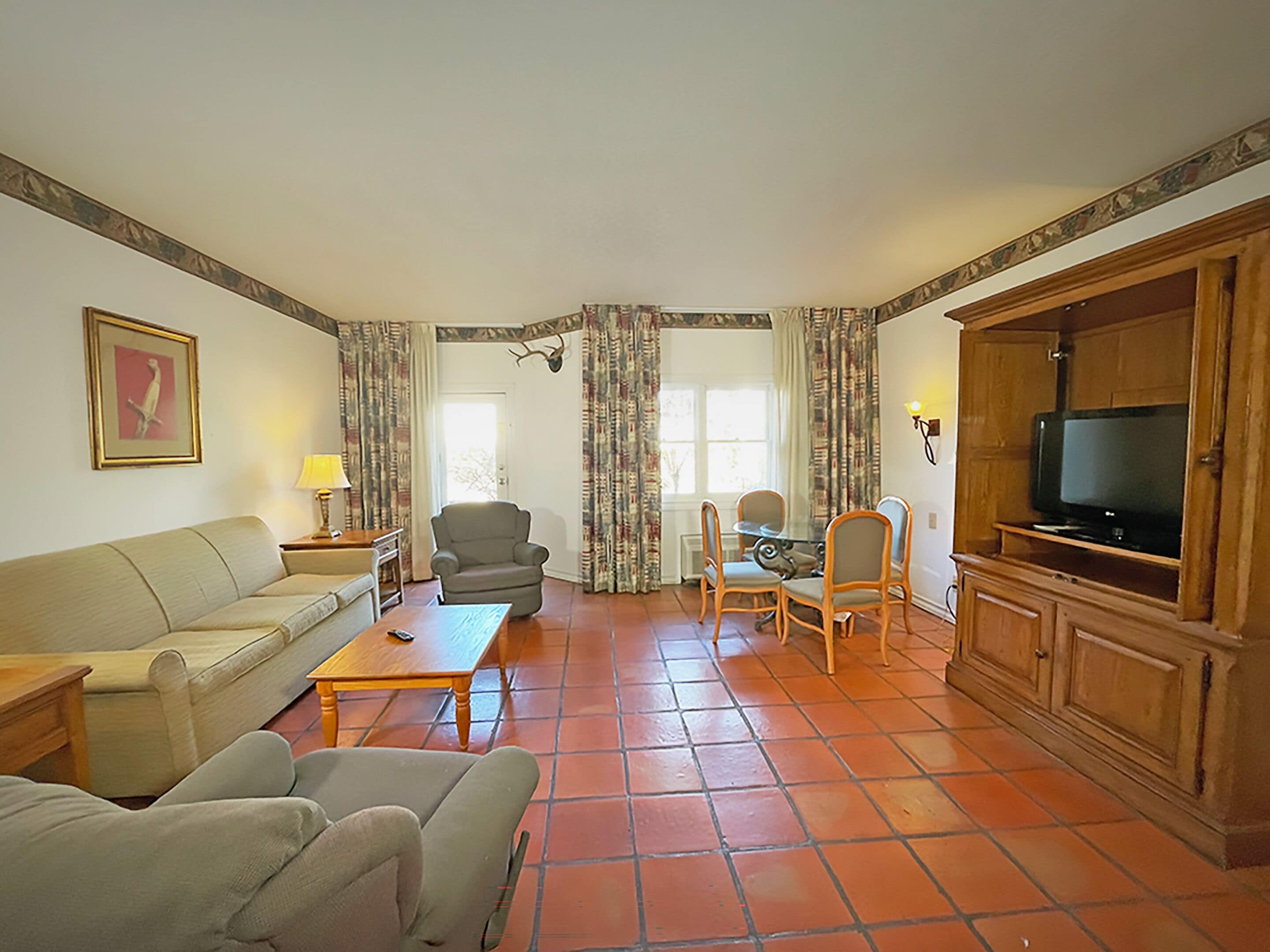 Una sala de estar con sofá, sillones, una mesa de centro, una mesa de comedor con sillas, televisor y chimenea.