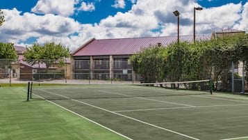 A tennis court with a net, surrounded by trees and buildings.
