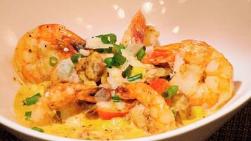 A bowl of shrimp with vegetables and a creamy sauce.