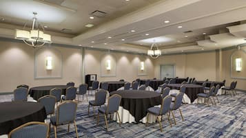 A conference room with round tables, chairs, and chandeliers.