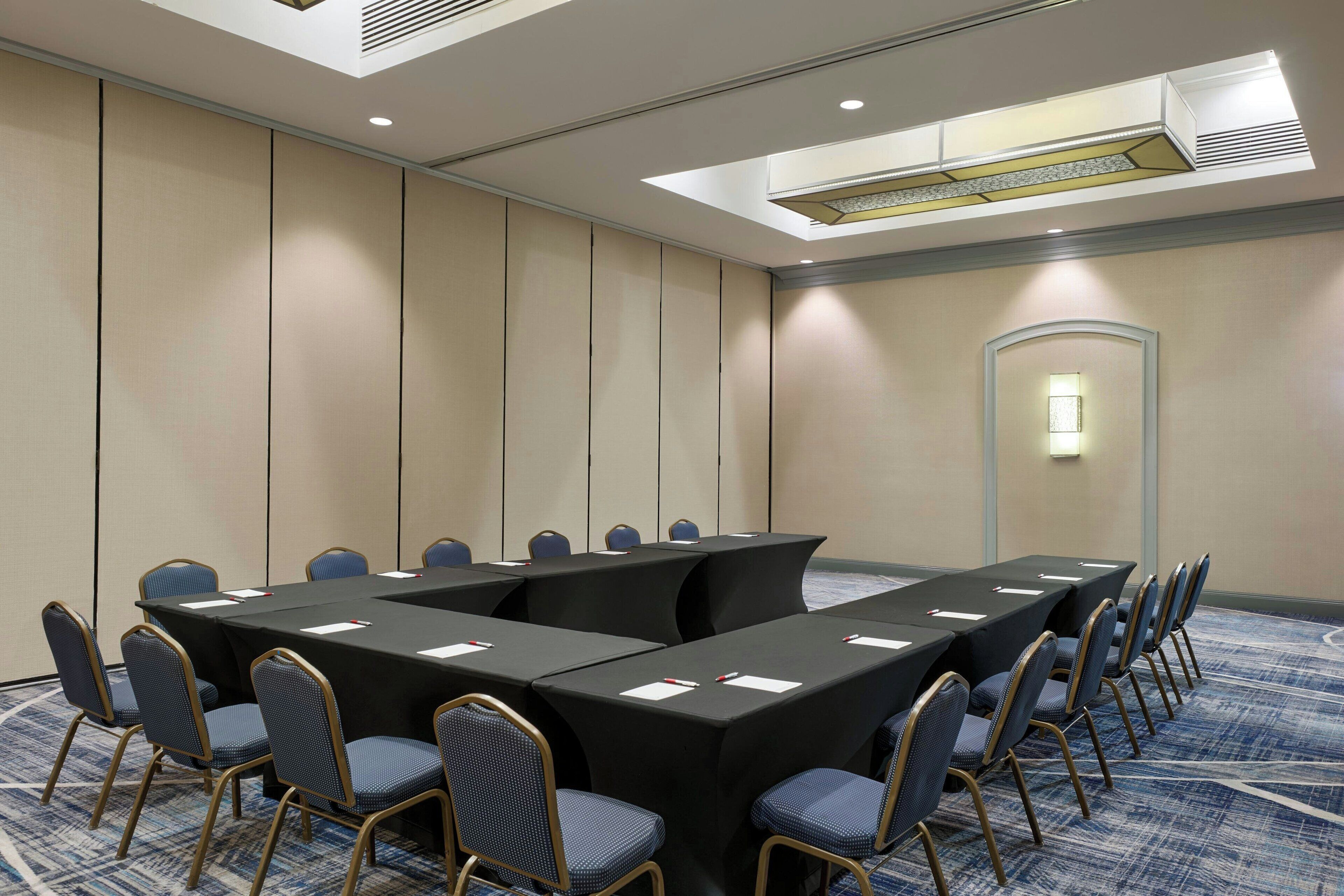 A conference room with a long table, chairs, and a carpeted floor.