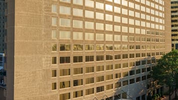 A modern Marriott hotel building with a grid of windows, a flat roof, and a parking area with cars.