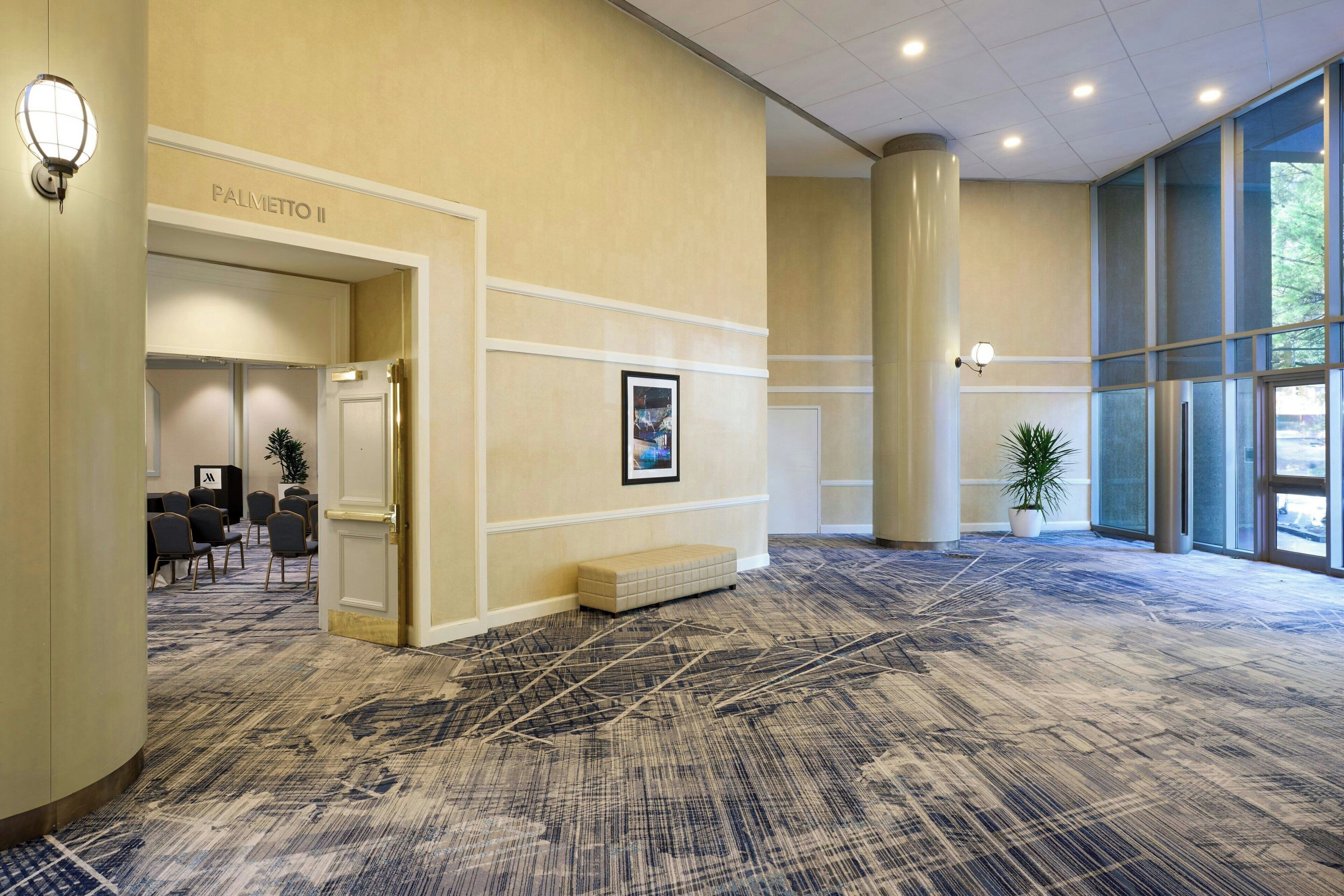 A spacious lobby with a patterned carpet, a seating area, and a reception desk.
