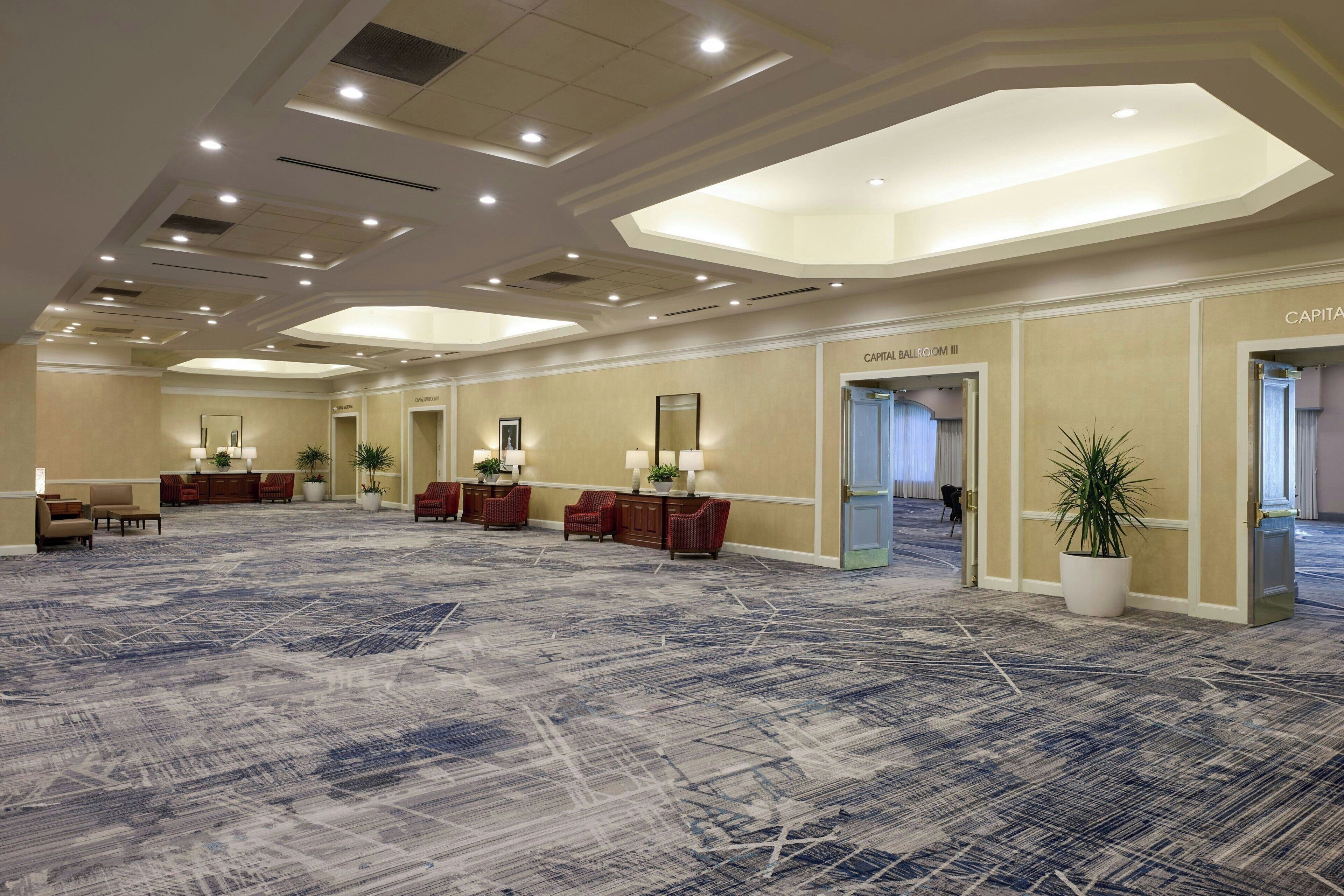 A spacious lobby with a patterned carpet, seating areas, and a reception desk.