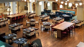 A modern restaurant with multiple dining areas, including booths and tables, and a central seating area with a blue sofa. - Marriott Columbia (Columbia)
