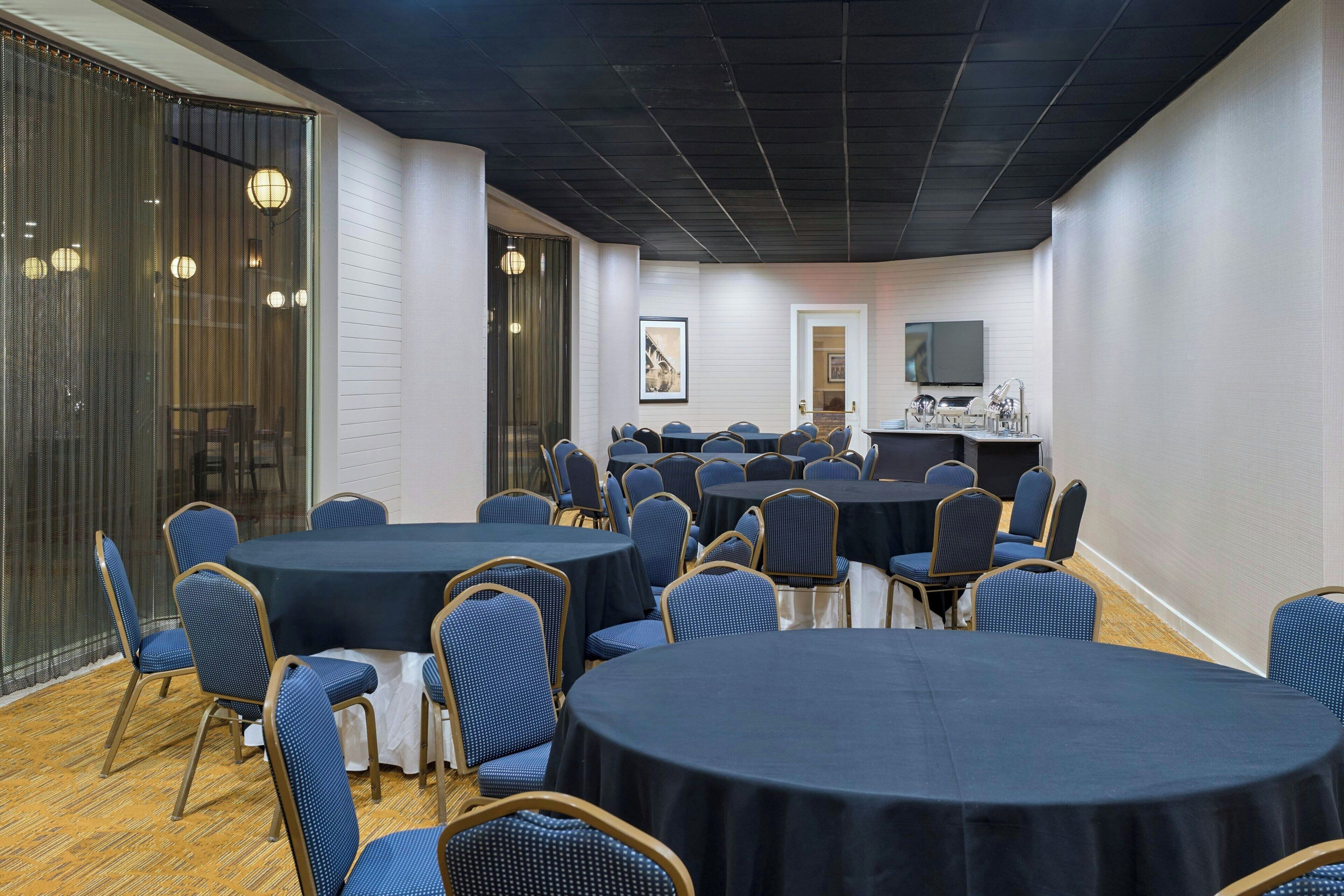 A conference room with multiple tables and chairs, a television, and a framed picture on the wall.