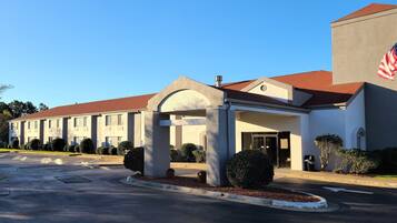 A hotel with a modern architectural design, featuring a prominent entrance with a covered area and a flag.