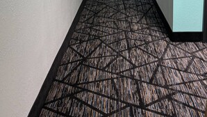 A long, narrow hotel corridor with patterned carpet, light-colored walls, and a visible room number sign. - Quality Inn Lavonia I-85 (Lavonia)