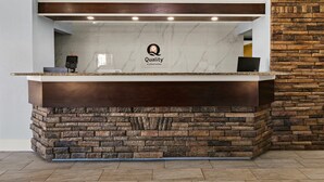 A reception desk with a marble top and a stone base, a logo for 'Quality by Choice Hotels', and a digital device on the counter. - Quality Inn Lavonia I-85 (Lavonia)
