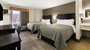 A hotel room with two beds, a desk, and a TV. - Quality Inn Lavonia I-85 (Lavonia)