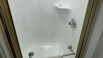 Un baño con cabina de ducha de vidrio, un perchero y un estante con artículos de aseo.