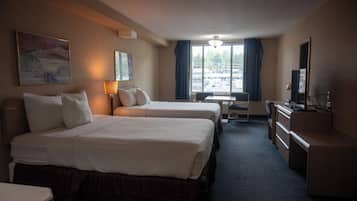 Een hotelkamer met twee bedden, een bureau, een stoel, een televisie en een raam met gordijnen.