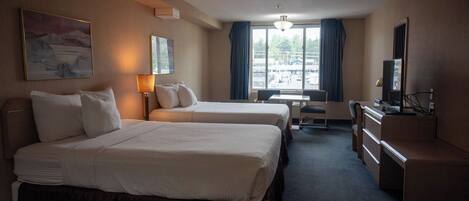A hotel room with two beds, a desk, a chair, a television, and a window with curtains.