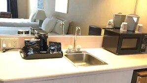 Una cocina compacta con lavamanos, microondas y cafetera.