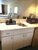 A compact kitchen with a sink, microwave, and coffee maker.