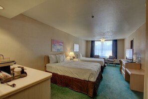 A hotel room with two beds, a desk, a chair, a TV, and a window with curtains.
