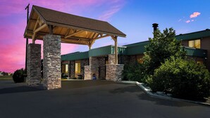 Ein Hotel mit überdachter Eingangspartie, Säulen aus Stein und einem begrünten Dach.