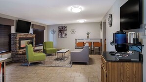 Ein modernes Wohnzimmer mit Kamin, grünen und grauen Sofas, einem Couchtisch und einem an der Wand montierten Fernseher.