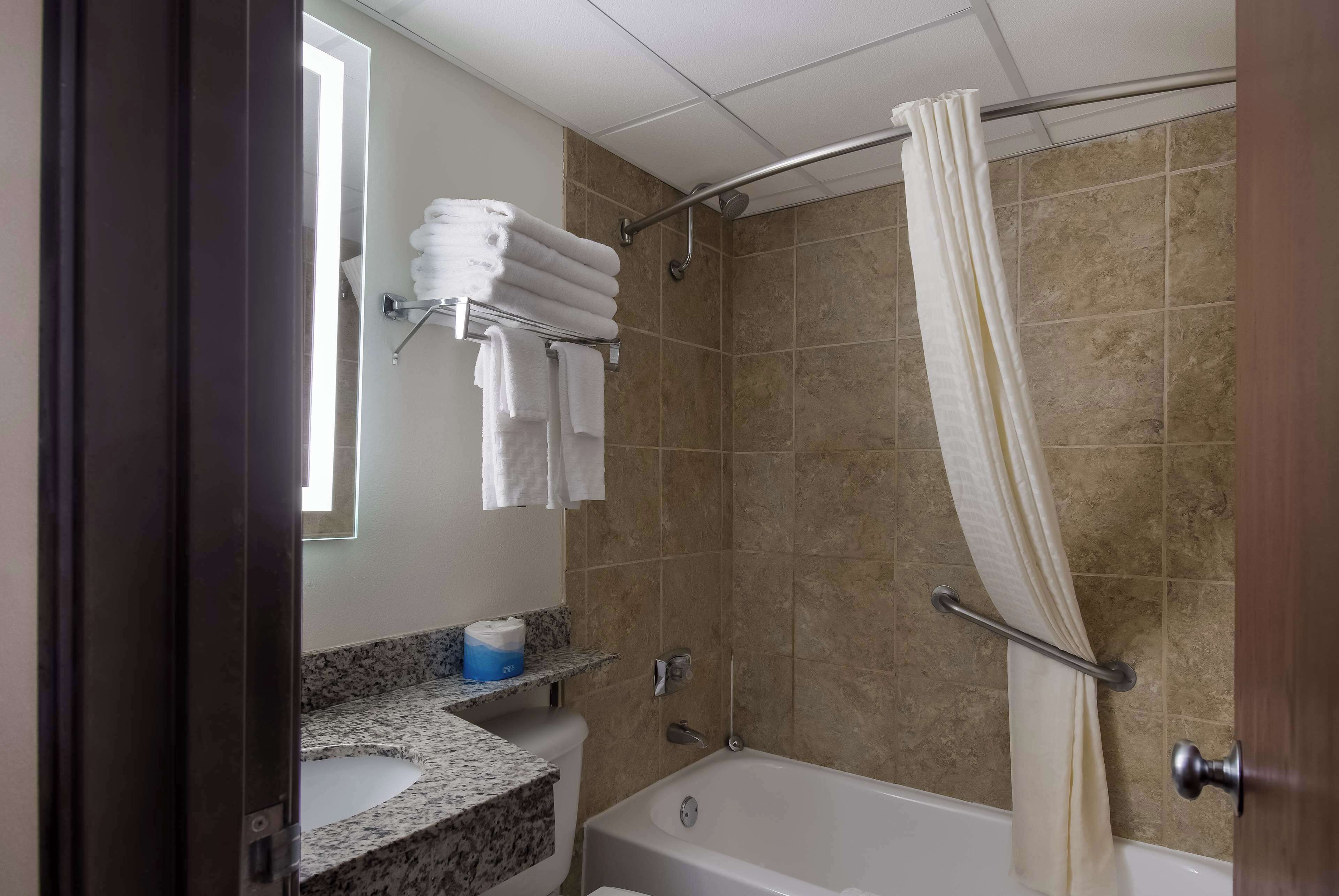 Un baño con bañera, ducha con cortina, toallero con toallas y un inodoro.