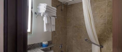A bathroom with a bathtub, a shower with a curtain, a towel rack with towels, and a toilet.