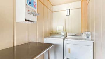 A laundry room with two washing machines and a coin-operated dryer.