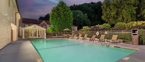 Una piscina al aire libre, sombrillas, sillones reclinables de piscina