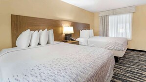 A hotel room with two beds, a wooden headboard, a nightstand with a lamp, and a large window with curtains. - Best Western Mountainbrook Inn (Maggie Valley)