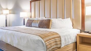 A hotel room with a large bed, wooden headboard, bedside tables, and lamps.