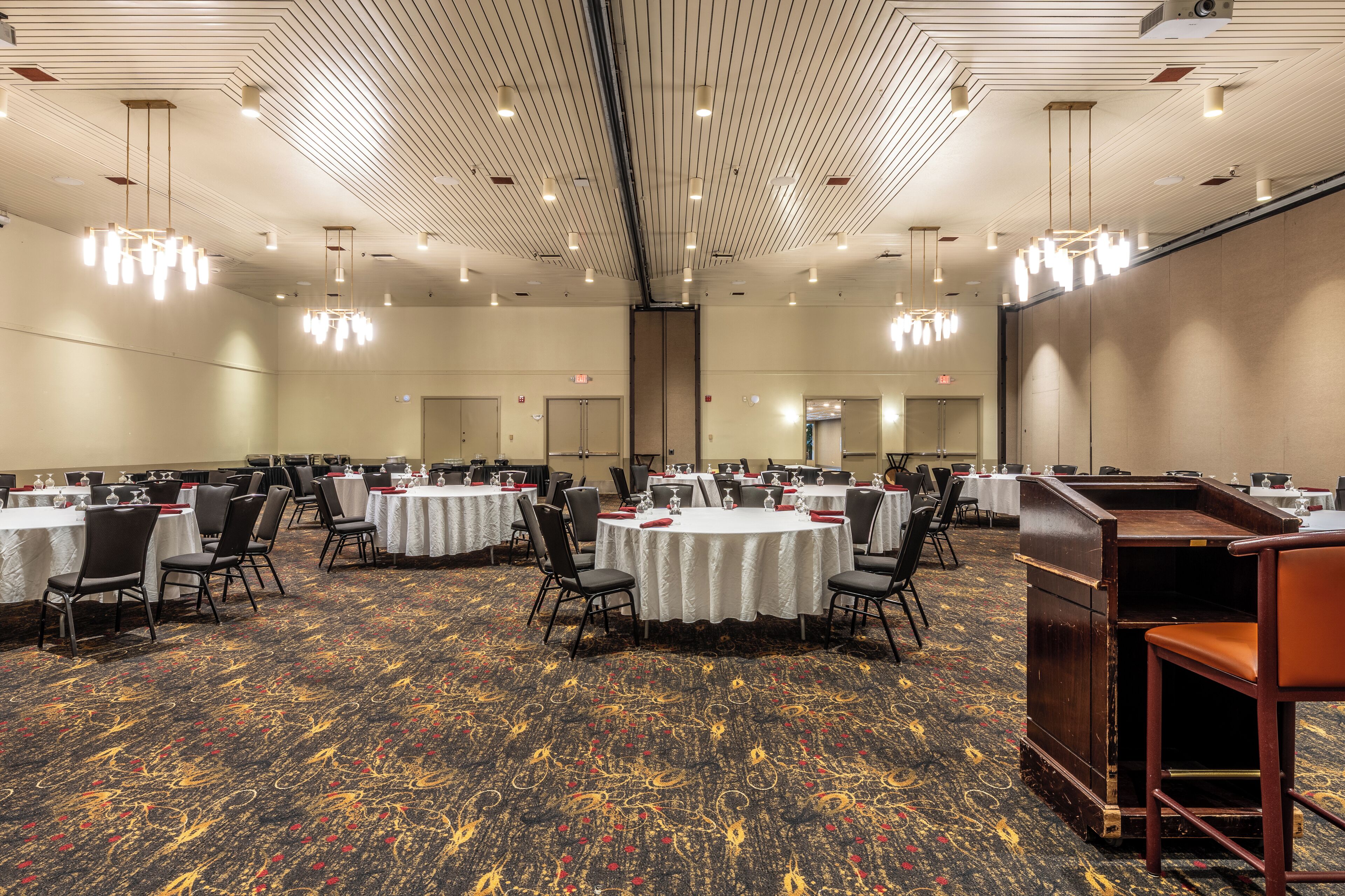 A large conference room with round tables, chairs, and a carpeted floor.
