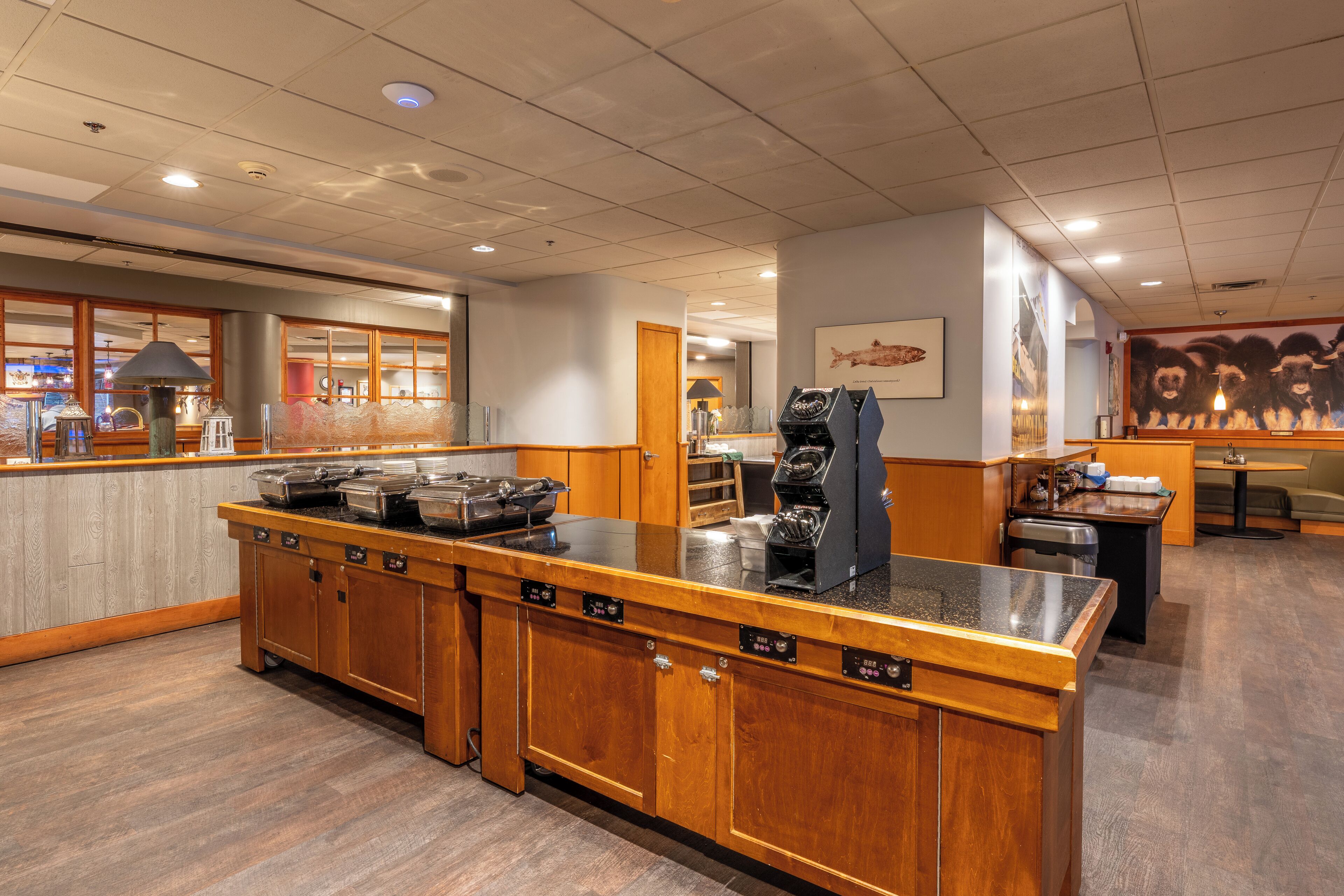A hotel kitchen with a long counter, wooden cabinets, and a coffee machine.