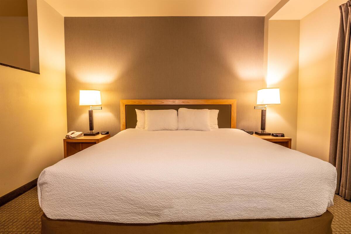 Une chambre d’hôtel avec un grand lit, deux lampes de chevet, un téléphone et une table de chevet.