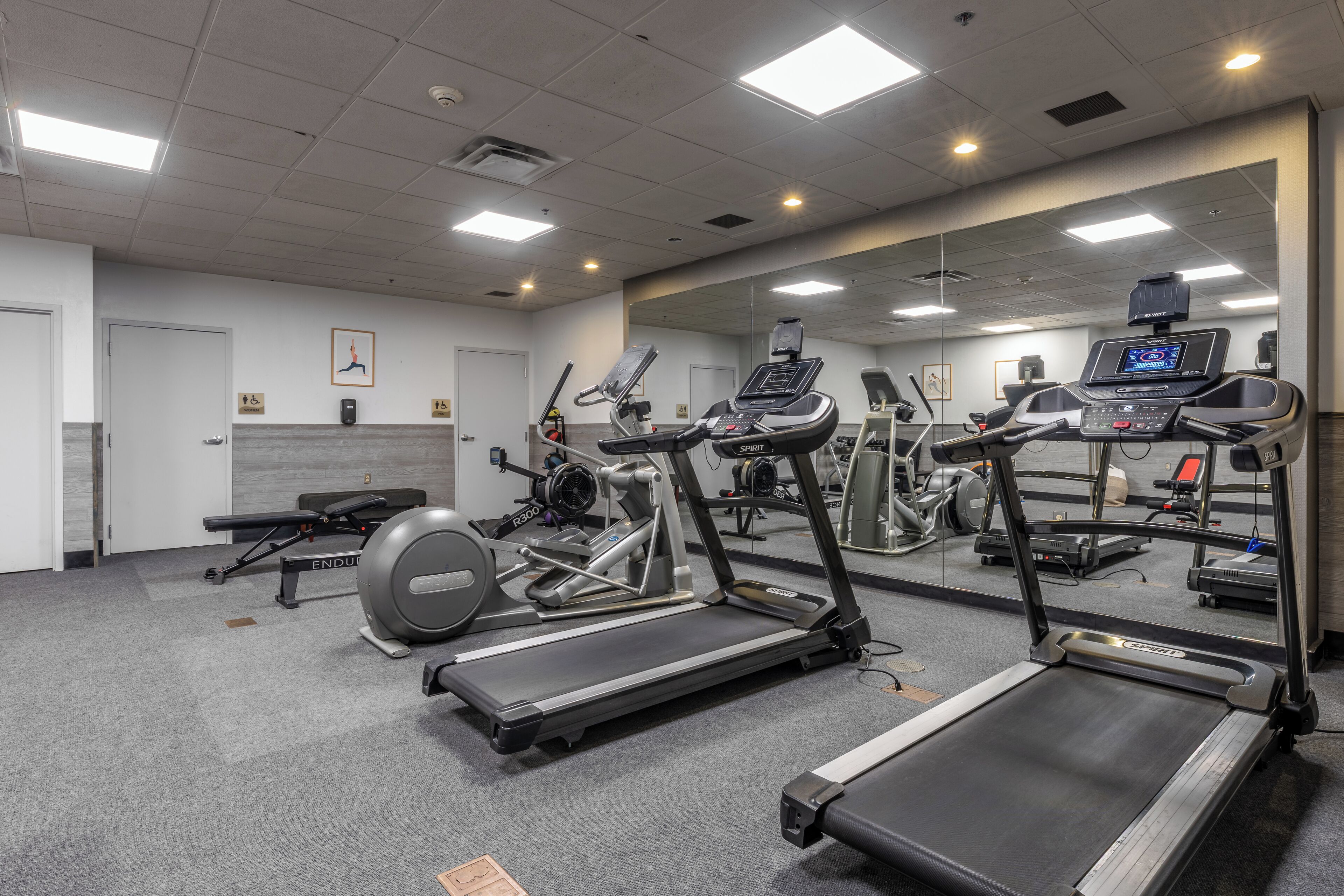 Une salle de sport équipée de tapis de course, de vélos elliptiques et d’un banc de musculation.