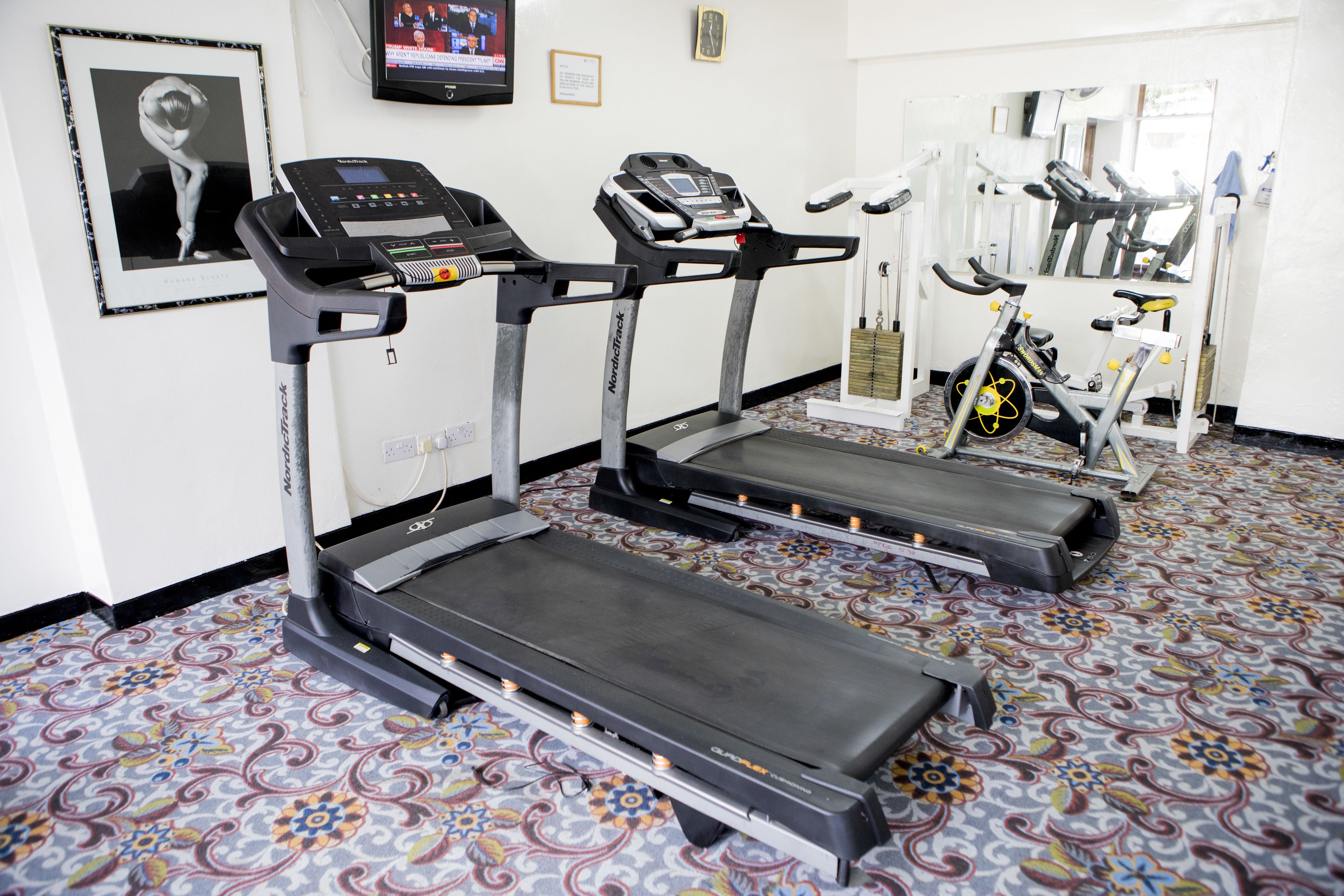 A gym with treadmills, a stationary bike, and a wall-mounted TV.