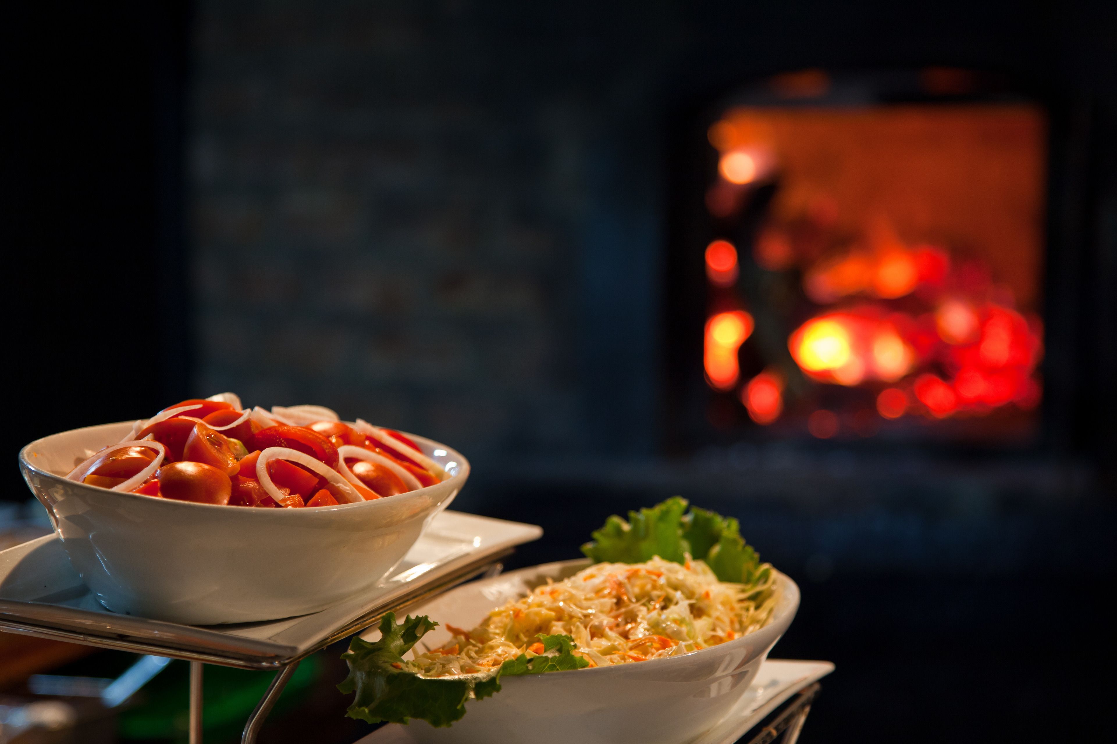 Two bowls of food on a tray, with a blurred background of a fireplace.