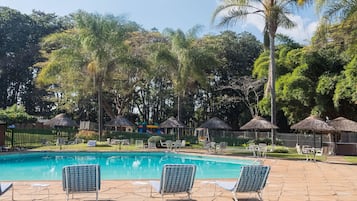 Una piscina al aire libre, sombrillas, sillones reclinables de piscina